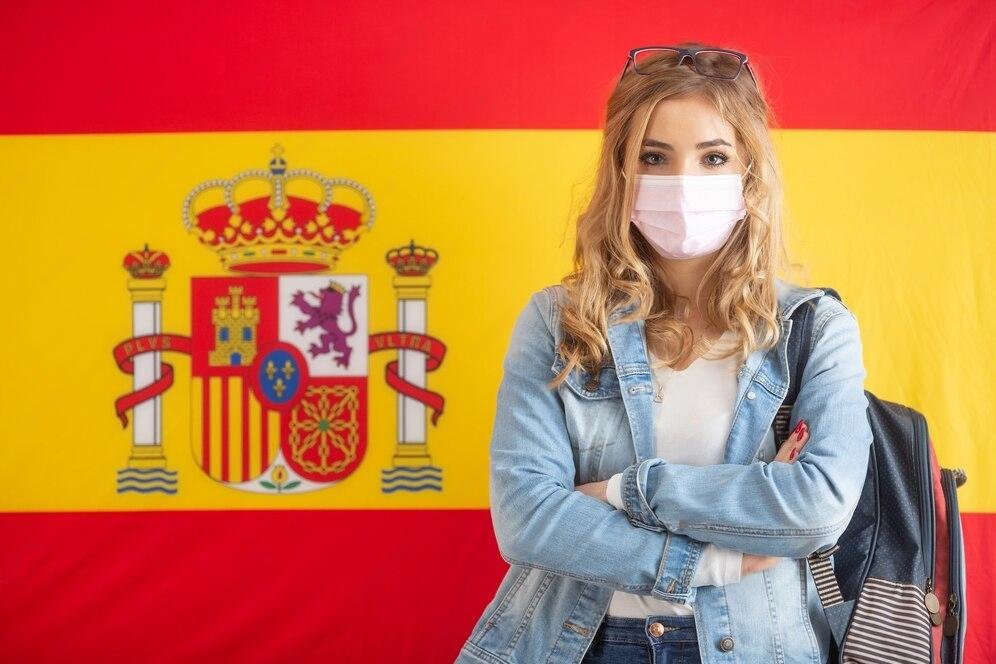 female-student-caryying-backpack-stands-front-spanish-flag-with-face-mask_341862-671-transformed